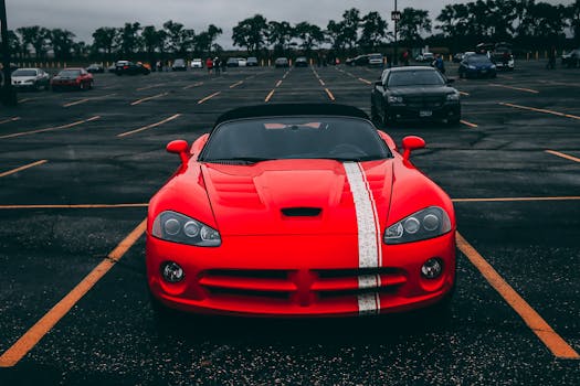 Vibrant red sports car parked in an empty lot with overcast skies.